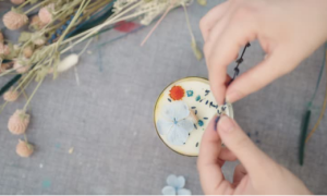 Pressed flowers being arranged on a candle, part of a candle making kit craft to elevate its look.